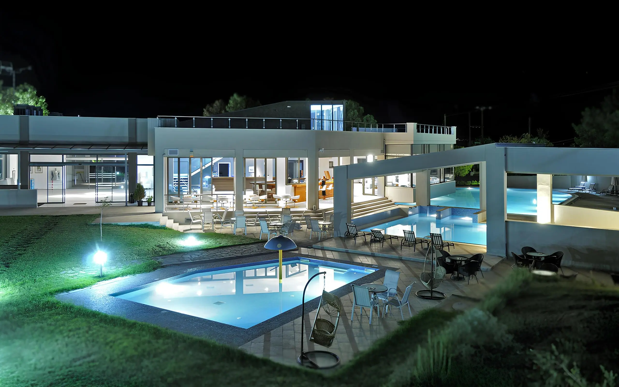 Νυχτερινός αρχιτεκτονικός φωτισμός ξενοδοχείου με φωτισμένη πισίνα στη Σιθωνία